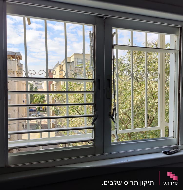 תריסים לבנים עם סורגים בחלון פתוח